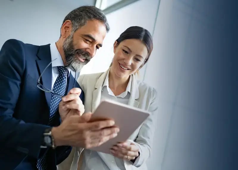 two marketing researchers using a tablet to analyze their survey incentive program.