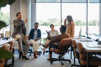 Employees feeling happy huddled up together discussing new year resolutions that support employee wellness at the office