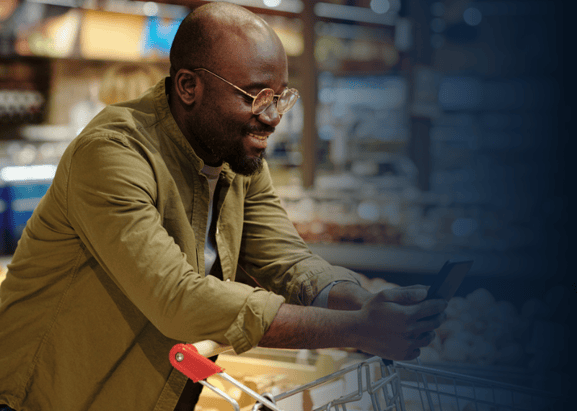 man using phone while grocery shopping