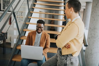 two young employees sitting on the stairs in a small office