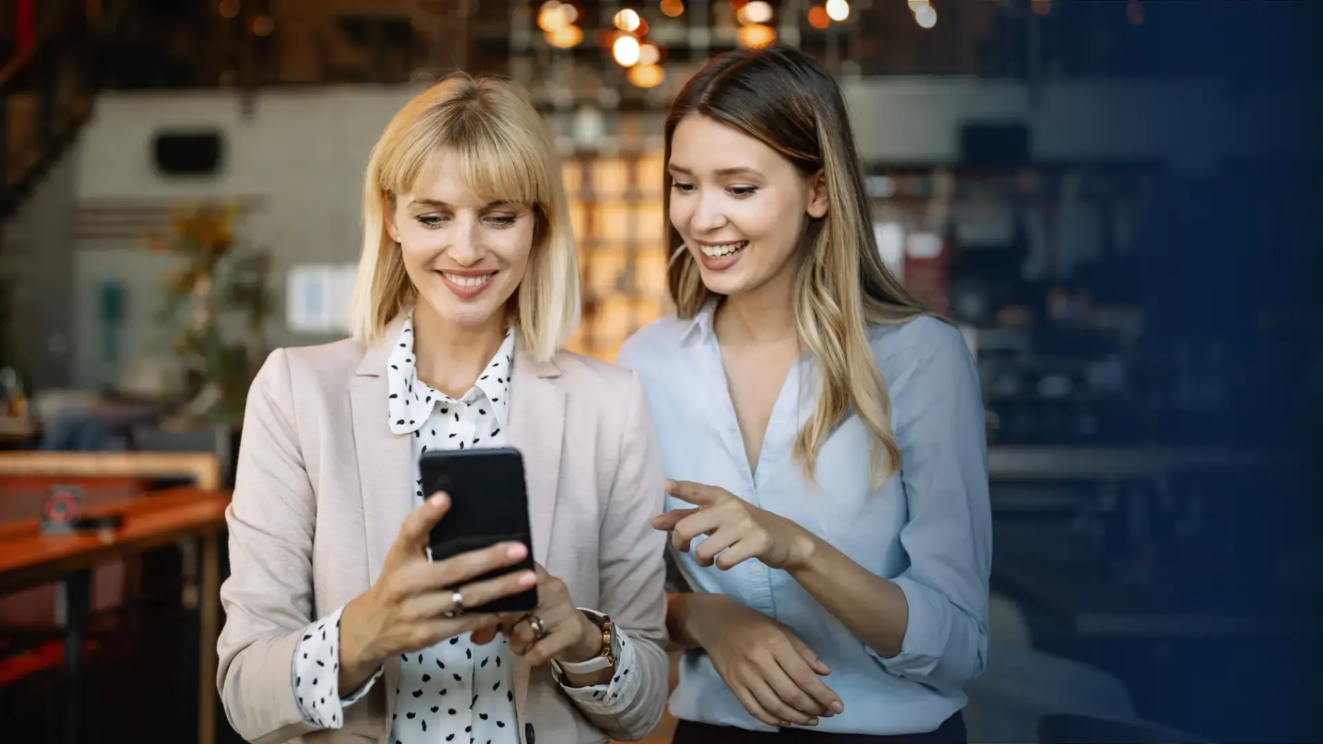 two happy female employees looking at their phone